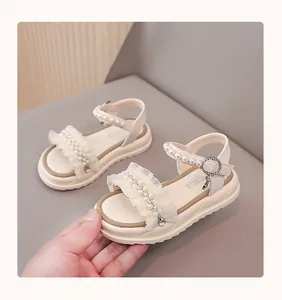 Close-up of girls' sandals featuring elegant pearl and lace ruffles on a beige strap
