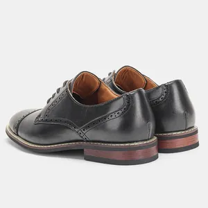 Rückansicht schwarzer Derby-Schuhe aus Leder mit Brogue-Nähten und Absatz in Holzoptik