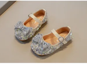 Close-up of sparkling rhinestones and elegant bow on girl's silver princess dress shoes