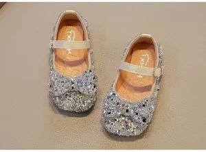 Macro view of sparkling silver rhinestone girl's princess shoes with cream buckle strap