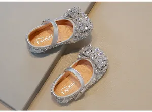 Macro view of girls silver rhinestone Mary Jane shoes featuring a large sparkling bow