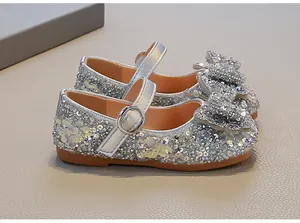 Close-up of girls' silver sequin princess shoes with decorative rhinestone bow