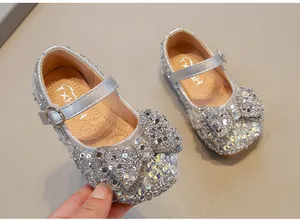 Detailed view of silver girls' princess shoes featuring a large sparkly rhinestone bow