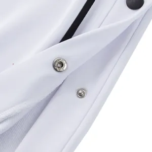 High-quality close-up of metallic snap buttons on white tear-away basketball sweatpants.