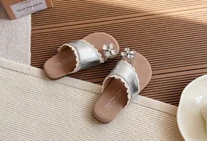 Primer plano de sandalias plateadas para niñas con flor de strass y ribete de encaje