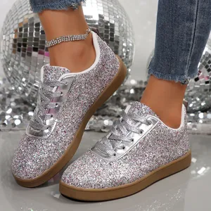 Close-up detail of women's sparkling silver glitter sneakers with metallic laces and gum sole