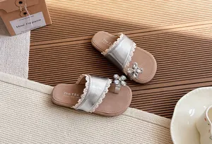 Primer plano de sandalias plateadas para niños con ribete de encaje y flor de strass