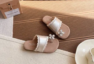 Detalle de sandalias planas de niña con ribete de encaje y flor de diamantes