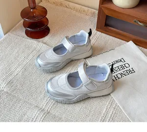 Detalle de zapatillas Mary Jane plateadas para niña con cierre de velcro sobre tela