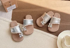 Vista detallada de sandalias para niñas con pedrería y encaje en plata y oro.