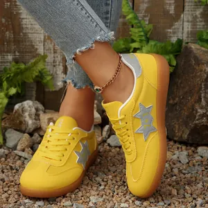 Detalle de zapatillas planas amarillas para mujer con parche de estrella gris al aire.