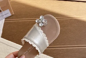 Detalle de sandalias para niña con ribete de encaje y una flor de pedrería brillante