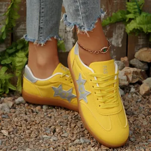 Primer plano de elegantes zapatillas planas de lona amarillas con estrellas en grava.