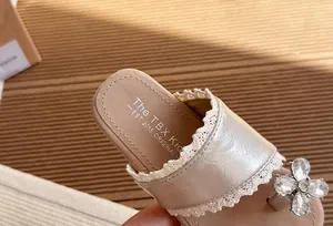 Detalle de primer plano de la flor de pedrería y el encaje en las sandalias de niña