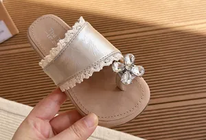 Vista detallada de sandalia champán para niña con encaje elegante y flor de strass