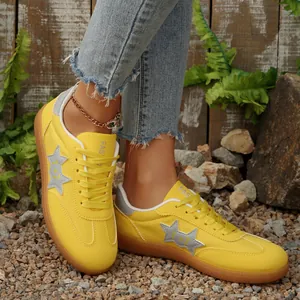 Primer plano de zapatillas amarillas de mujer con diseño de estrellas sobre grava