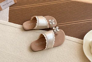 Detalle de sandalias doradas para niños con ribete de encaje y flor de cristal