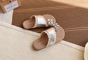Vista detallada de sandalias plateadas para niña con flor de strass brillante y encaje.