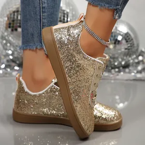 Close-up detail of gold glitter flat casual sneakers with sequin finish and brown sole