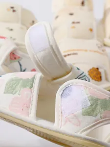 Gedetailleerde macro-opname van de klittenbandsluiting en bloemenstof op deze baby sandalen