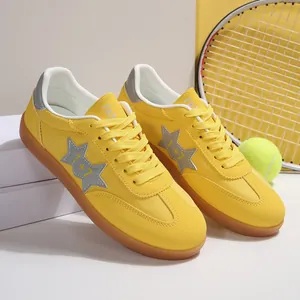 Zapatillas casuales de tela amarilla con raqueta y pelota de tenis sobre bloque blanco