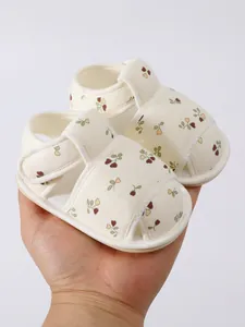 Detailopname van schattige babysandalen met bloemenpatroon in de hand gehouden
