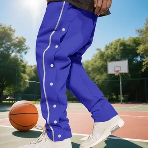 Men's royal blue heavyweight basketball tear-away pants on a sunny outdoor court
