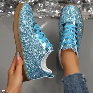 Close-up detail of blue glitter sneakers with a shiny sequin finish and blue laces.