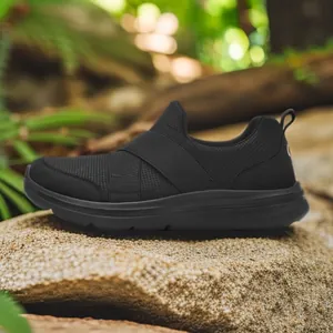 Black breathable mesh slip-on sneakers with elastic cross straps on outdoor rock