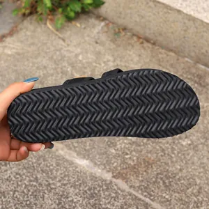 Detaillierte Makroansicht der rutschfesten Gummisohle für schwarze flache Slipper.