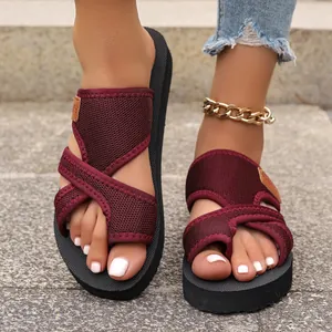Nahaufnahme der weinroten Zehensteg-Sandalen aus Mesh-Gewebe an den Füßen.