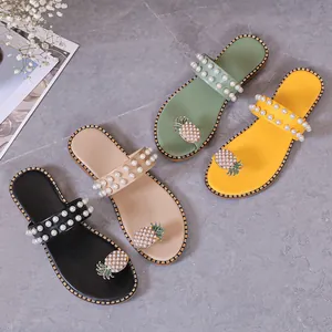 Close-up of four colors of flat sandals with pearl straps and pineapple rhinestone decor