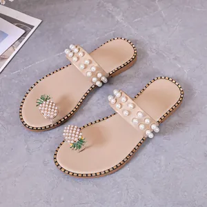 Elegant beige flat sandals featuring pearl-studded straps and a pineapple rhinestone charm