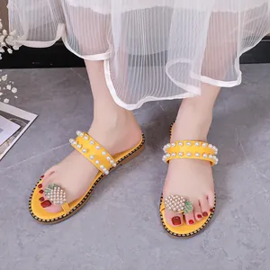 Detailed view of yellow flat slides with pearl straps and pineapple rhinestone accent.