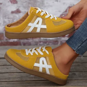 Primo piano di sneaker mule in mesh giallo con logo A bianco e lacci decorativi