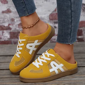 Primo piano di scarpe sportive gialle in mesh con lacci bianchi e jeans.