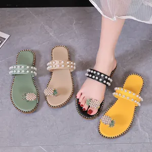 Detail view of women's flat summer sandals with rhinestone pineapple and pearls