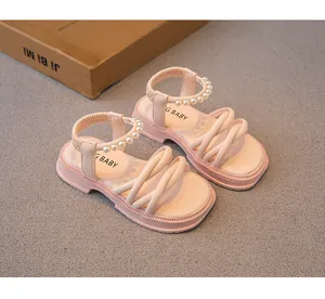 Dettaglio di eleganti sandali rosa da bambina con cinturini in perle e suole morbide e flessibili.