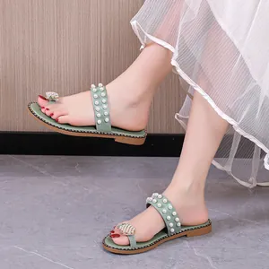 Detailed view of light green flat sandals with pineapple rhinestone and pearl accents