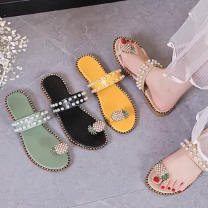 Detailed view of women's flat sandals with pineapple rhinestone and pearl accents.