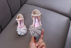 Nahaufnahme rosa Mädchenschuhe mit Glitzer-Schleife, Strass und Perlenriemen
