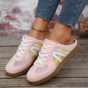 Primo piano di sneakers mule rosa da donna con dettagli in mesh e lacci bianchi.