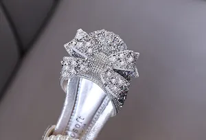 Detaillierte Nahaufnahme von silbernem Mädchenschuh mit Strass- und Perlenbesatz.