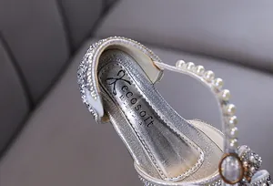 Detailansicht silberner Mädchen-Prinzessinnenschuhe mit Perlen und Glitzersteinen.