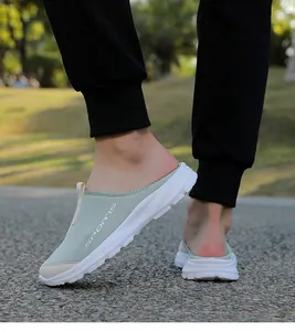 Close-up of sage green breathable slip-on mule sneakers with white sole on outdoor path.