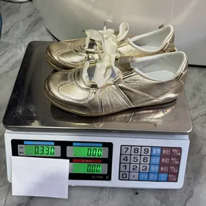 Détail des baskets plates dorées pour femmes montrant le poids sur une balance numérique