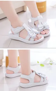 Vista detallada de sandalias blancas para niñas con lazo de mariposa de diamantes brillantes