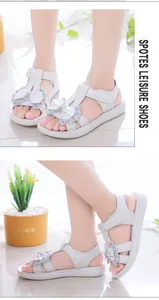 Primer plano de elegantes sandalias blancas de princesa para niñas con un lazo decorativo y pedrería