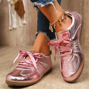 Gros plan sur des baskets métallisées roses avec des lacets en ruban de satin.