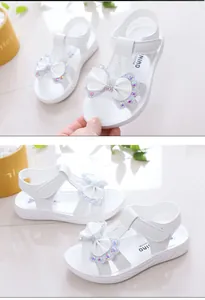 Vista detallada de sandalias blancas para niñas con elegantes lazos de pedrería